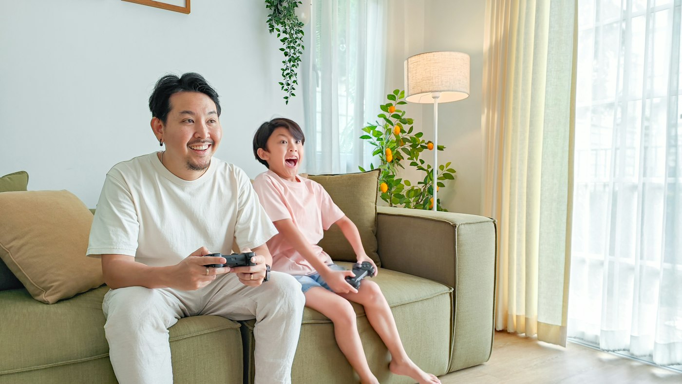 Father and son laughing while playing video games at home