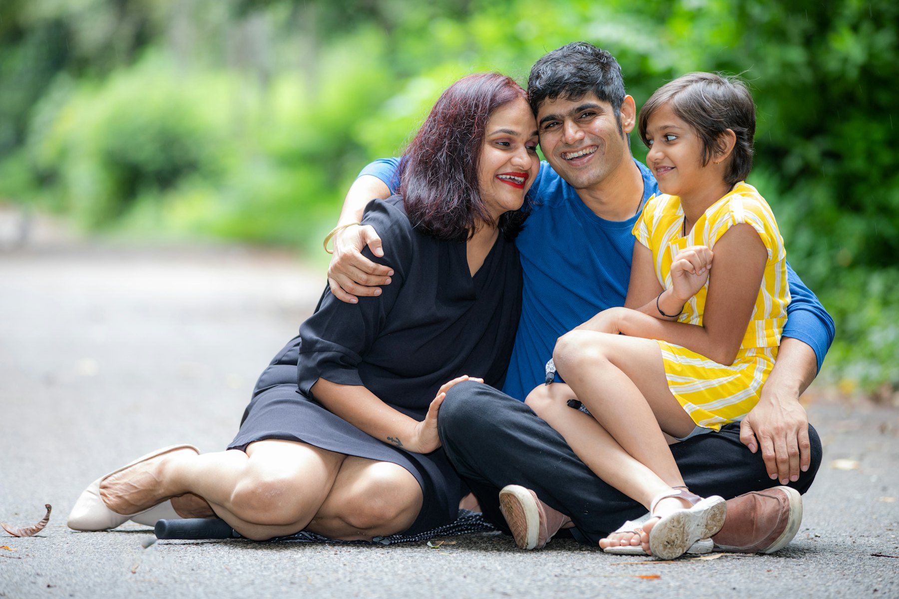 Mother, father and daughter hugging while sitting outdoors