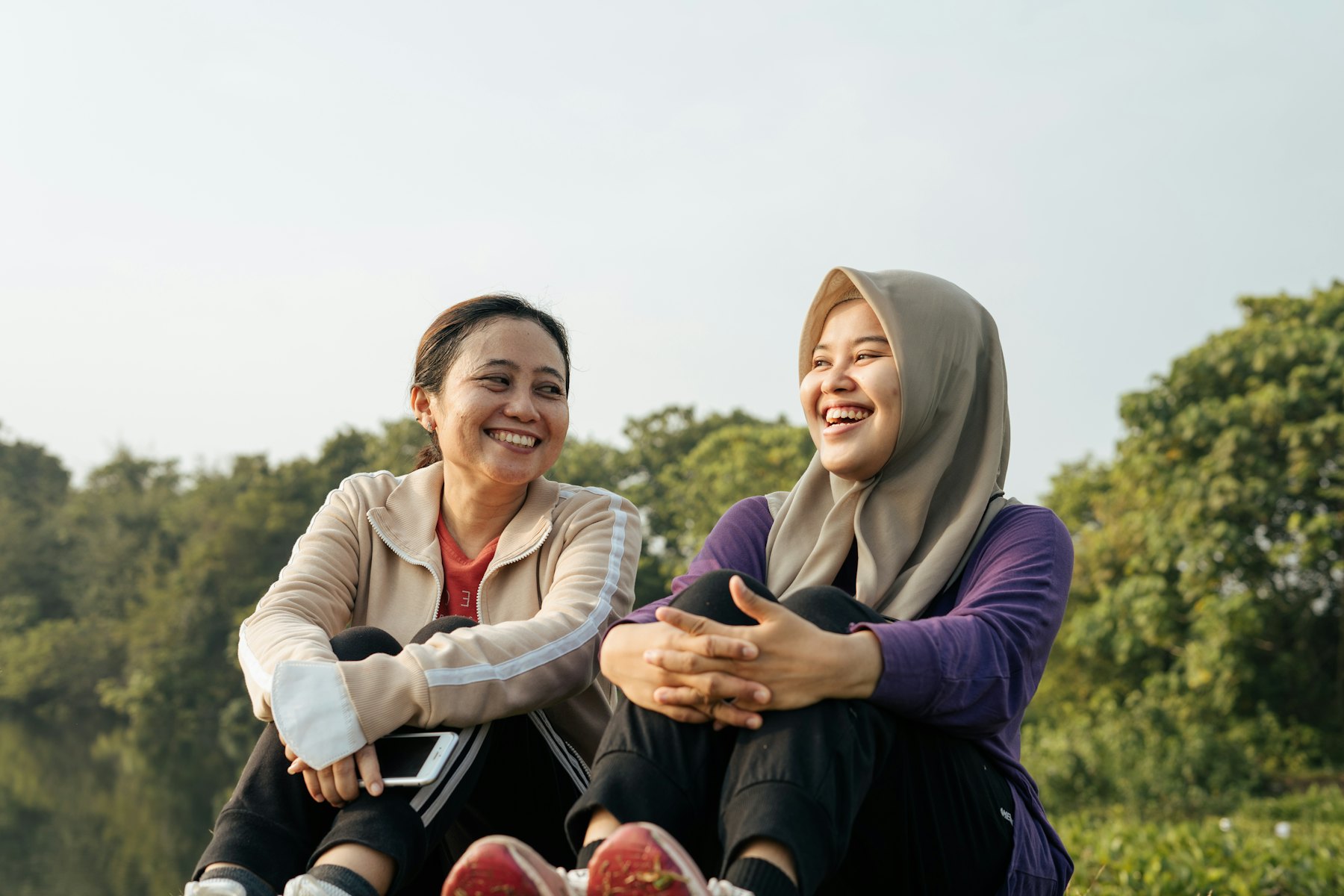 Two Muslim women laughing together outdoors