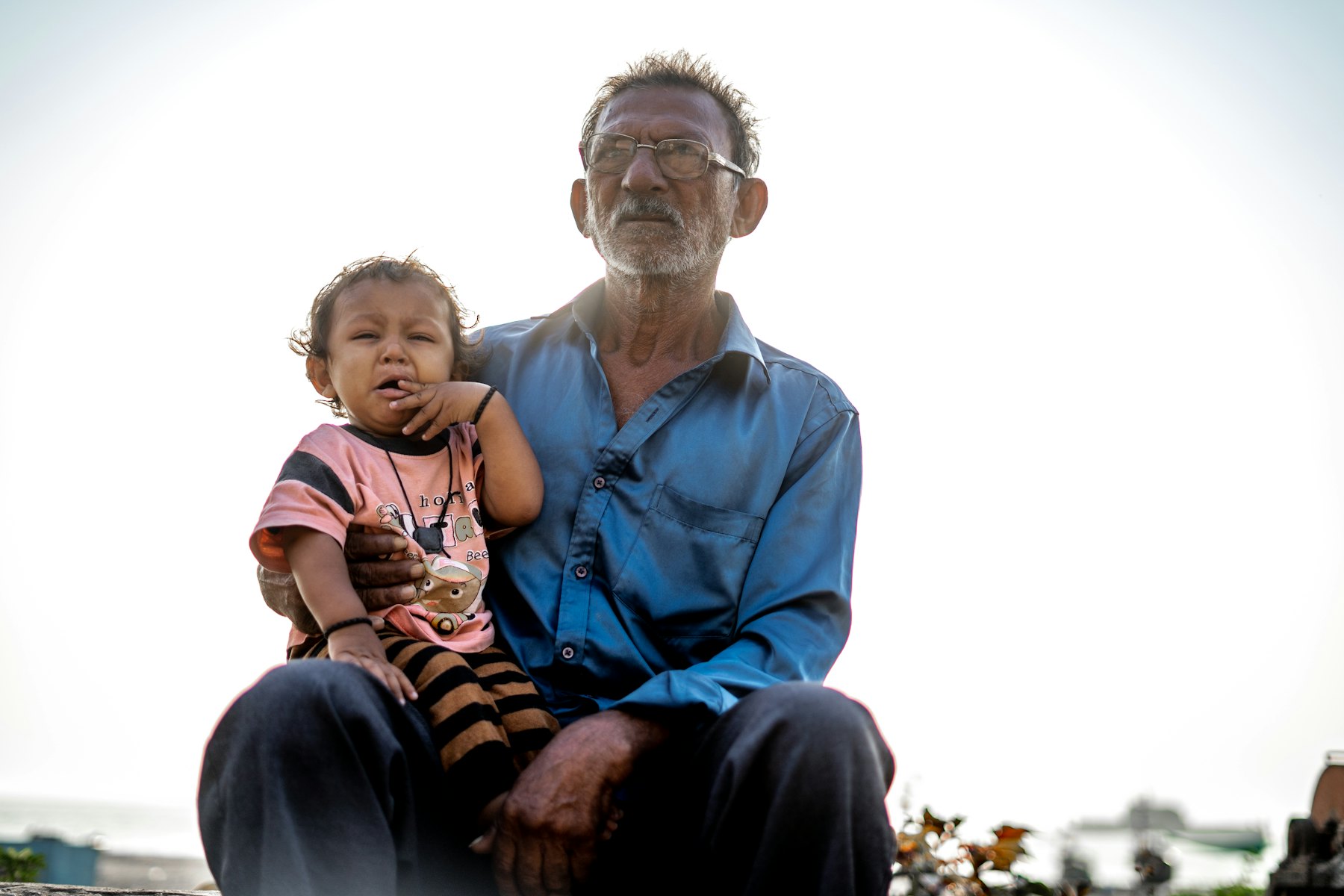 Grandfather sitting outdoors with his granddaughter on his lap
