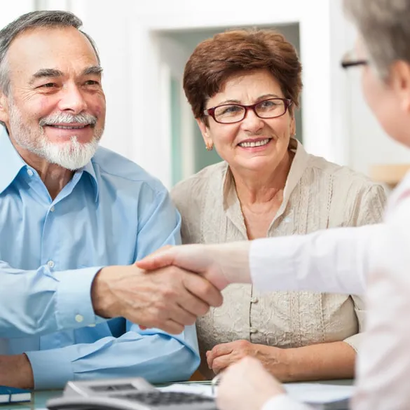 Elderly couple shaking hands with their estate planner