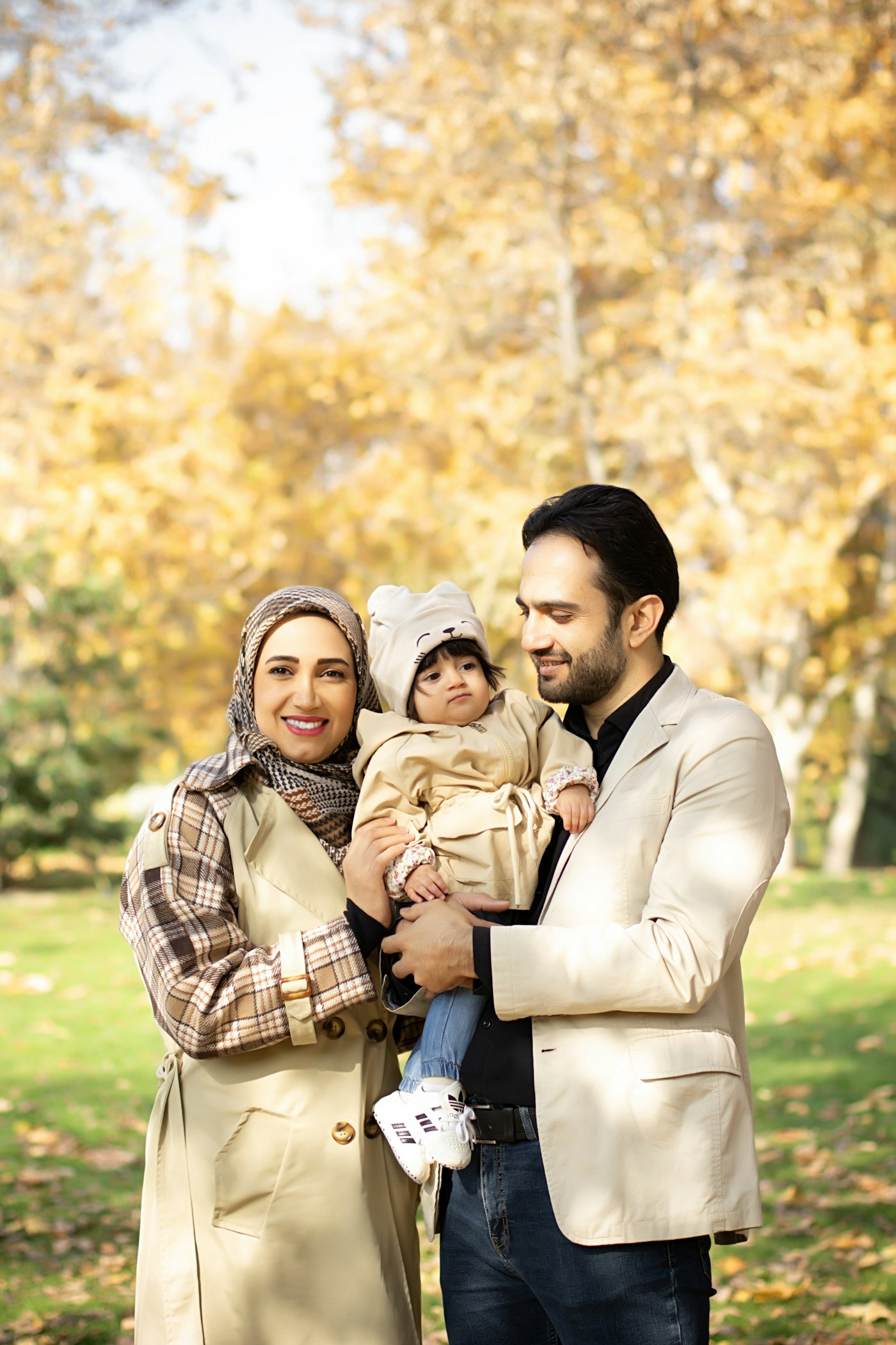 Muslim family holding their baby in an autumn park